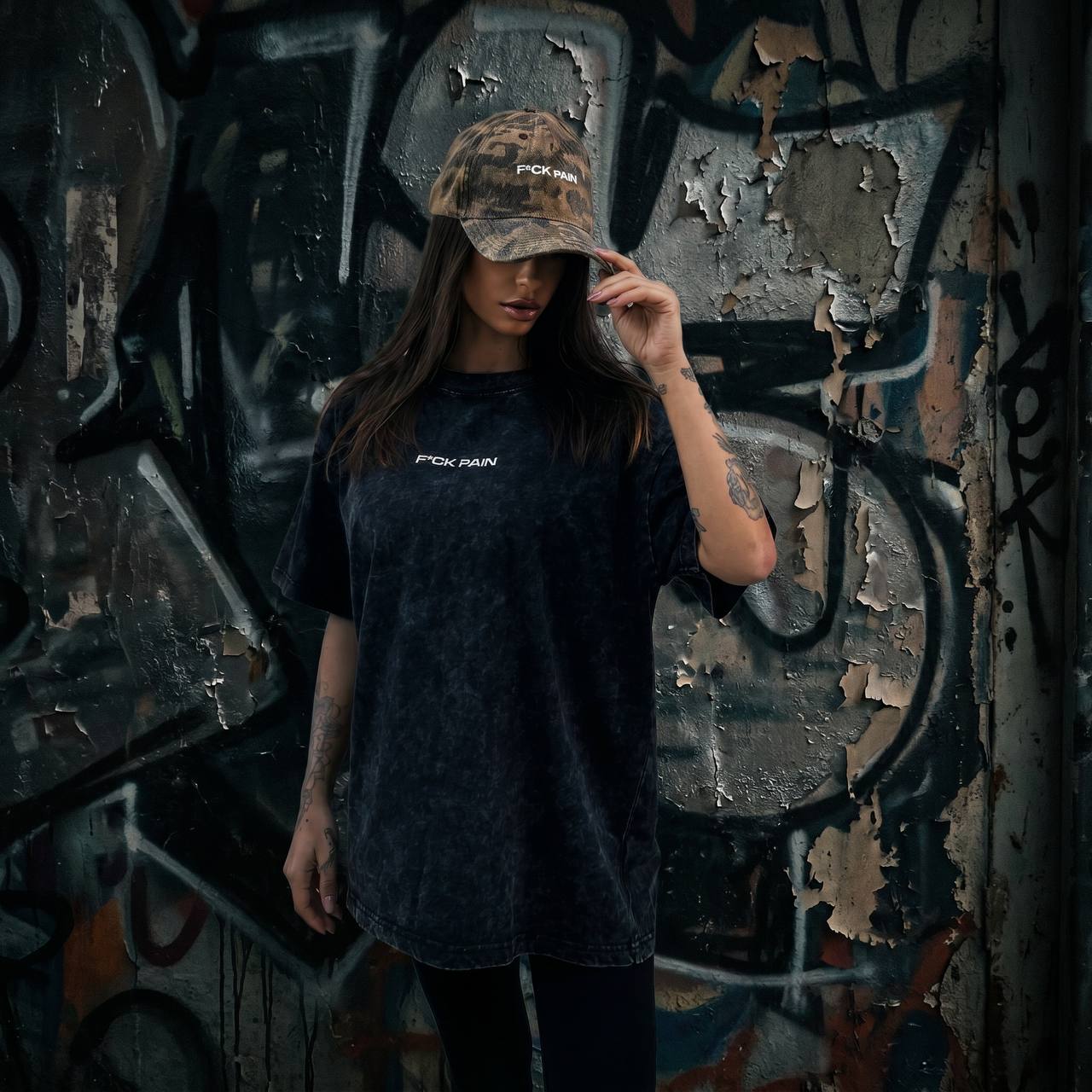 F*CK PAIN Distressed Camo Cap — female lifestyle front graffiti wall